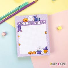 a notepad with an image of cats and pumpkins on it next to some pencils