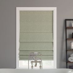 a bath tub sitting next to a window covered in roman shades