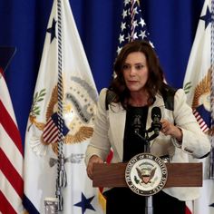 a woman standing at a podium in front of american flags