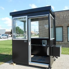 a portable phone booth sitting in front of a brick building next to a parking lot