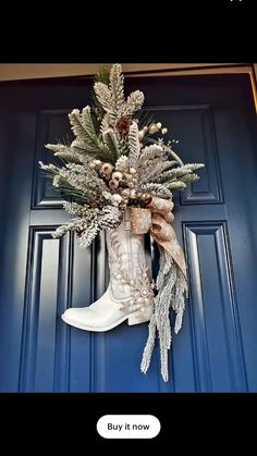 a boot decorated with pine cones and evergreens hangs on the front door's blue door