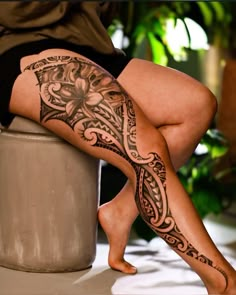 a woman is sitting on a stool with her legs crossed and tattoos on the leg