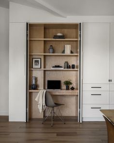 a wooden desk sitting in front of a white book shelf filled with books and other items