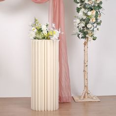 two vases with flowers are sitting next to each other on the floor in front of pink drapes