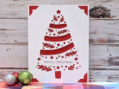 a card with a christmas tree on it sitting next to some ornaments and wood planks