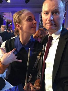 a man and woman standing next to each other holding an award in front of them