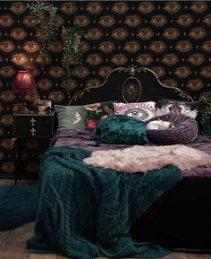 a bed with pillows and blankets on it in front of a wallpapered background