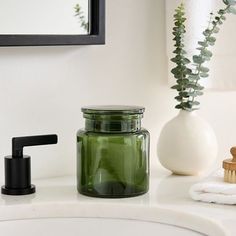 a green jar sitting on top of a bathroom counter next to a sink and mirror