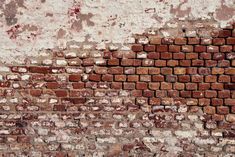 an old brick wall that has been painted red and white with paint chippings