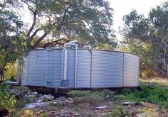 an old water tank sitting on the side of a road next to trees and rocks