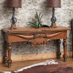 a wooden table with two lamps on top of it next to a cowhide rug