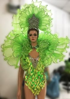 a woman in a green costume walking down the runway