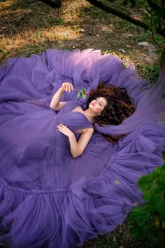 a woman in a purple dress laying on the ground