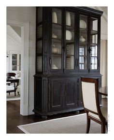 a black china cabinet with glass doors in a dining room