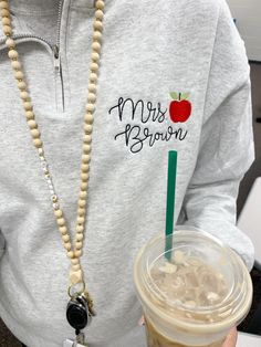 a person holding a drink and beaded necklace with an apple on the label that says mr brown