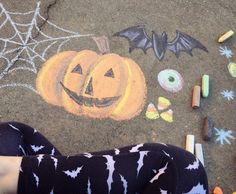 a child's feet standing on the ground with chalk drawings and crayons