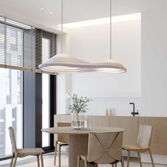 a dining room table with four chairs and a vase on the table in front of it