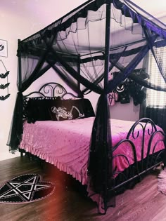 a bed with black netting and pink bedspread