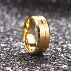 a gold wedding ring with two thin lines in the center on a glittery surface