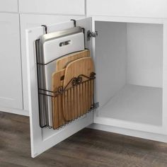 a kitchen cabinet with cutting boards and knives in the bottom drawer, which is open