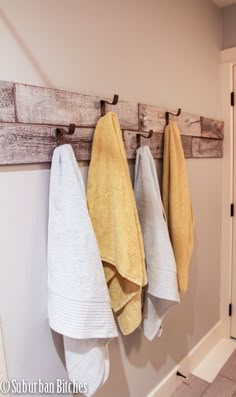 towels are hanging on the wall near two hooks and one is holding three folded towels