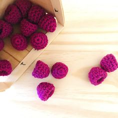 some crocheted strawberries are in a box on the table next to it