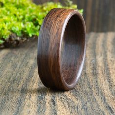 a wooden ring sitting on top of a wooden table next to green moss covered ground