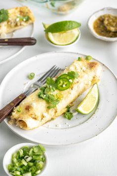 a white plate topped with fish next to small bowls of green vegetables and sauces