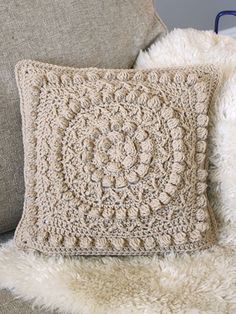 a crocheted pillow sitting on top of a couch