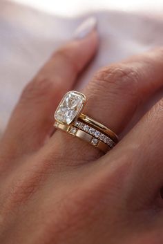 a woman's hand with two gold rings and a diamond ring on her finger