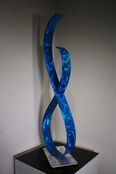 a blue sculpture sitting on top of a black table next to a white wall in a room