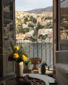 a balcony with flowers and potted plants on the table in front of an open window