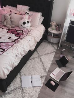 a bed with pink and black comforter, stuffed animals and notebooks on the floor