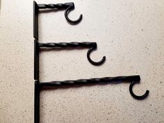 three black hooks are hanging on the wall with one hook in the shape of an umbrella