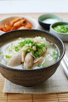 a bowl filled with soup and vegetables next to chopsticks