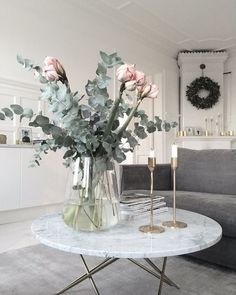 a living room filled with furniture and flowers on top of a white table in front of a gray couch