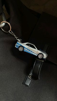 a keychain with a car on it is hanging from a black piece of luggage