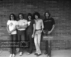 five young men are standing in front of a brick wall and posing for the camera