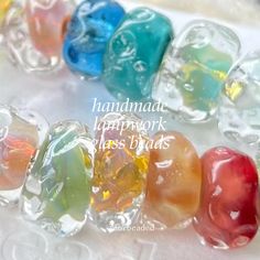 colorful glass beads are lined up on a white tablecloth with the words handmade happy work glass beads