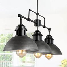 three lights hanging from the ceiling in a kitchen with white walls and windows behind them