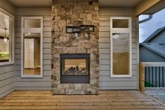 a large stone fireplace sitting on top of a wooden floor next to a window and door