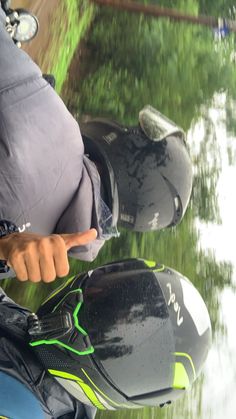 two people riding on the back of motorbikes in front of some grass and water