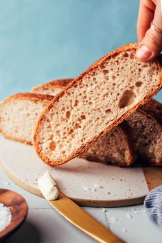 a person holding a piece of bread on top of a white plate