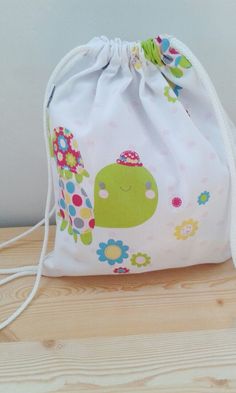 Bolsa mochila para bebe. Muy practica, puede usarse en muchas situaciones: para llevar la ropa de cambio a la guarderia, el sandwich, o los accesorios para el bebe (pañales, etc.). Es la bolsa perfecta para el dia a dia. Se puede lavar perfectamente en la lavadora. Muy suave y manejable. Hecha con tela estampada con tortugas y flores de colores sobre fondo blanco.Sin forrar. Las medidas son: Para niño: Ancho: 26 cm Alto: 30.5 cm Para adulto: Alto: 42,5 cm Ancho: 35 cm Cute Green Softback Bag, Cute Cotton Bags For Back To School, Playful Cotton School Bags, Casual Standard Backpack For Playtime, Playful Softback Bags For Back To School, White Standard Backpack For Gift, Cute Back To School Gift Bag, Casual White Bag For Playtime, Playful Softback School Bags