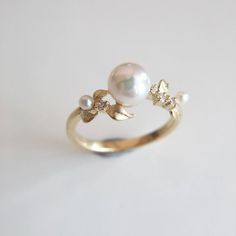 a pearl and diamond ring sitting on top of a table