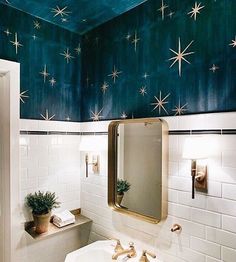 a bathroom with stars painted on the ceiling and white tile walls, along with a gold framed mirror