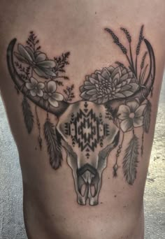 a bull skull with flowers and feathers on it's side tattoo by the artist