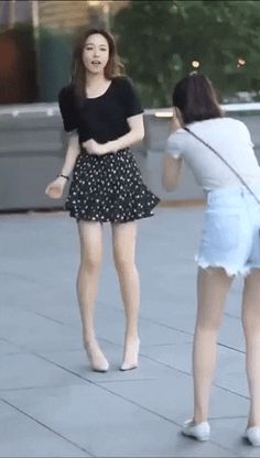 two young women are standing on the sidewalk