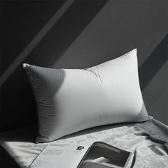 a white pillow sitting on top of a bed next to a book