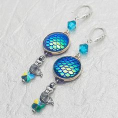 two fish dangles with blue and green glass beads are hanging from silver earwires